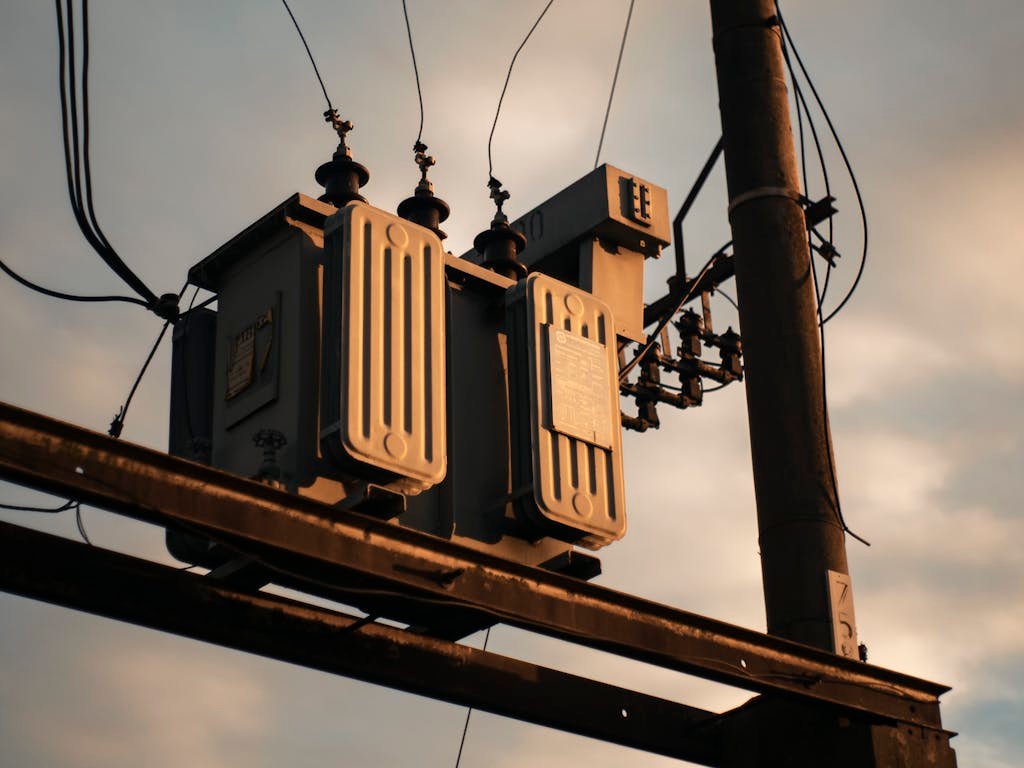 Nosotros 3 Close-up of an electrical transformer on a utility pole against a sunset sky.